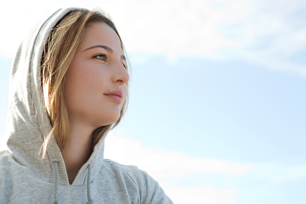 Close up portrait of a young woman wearing a hoodie who's in search of rehab for her addiction