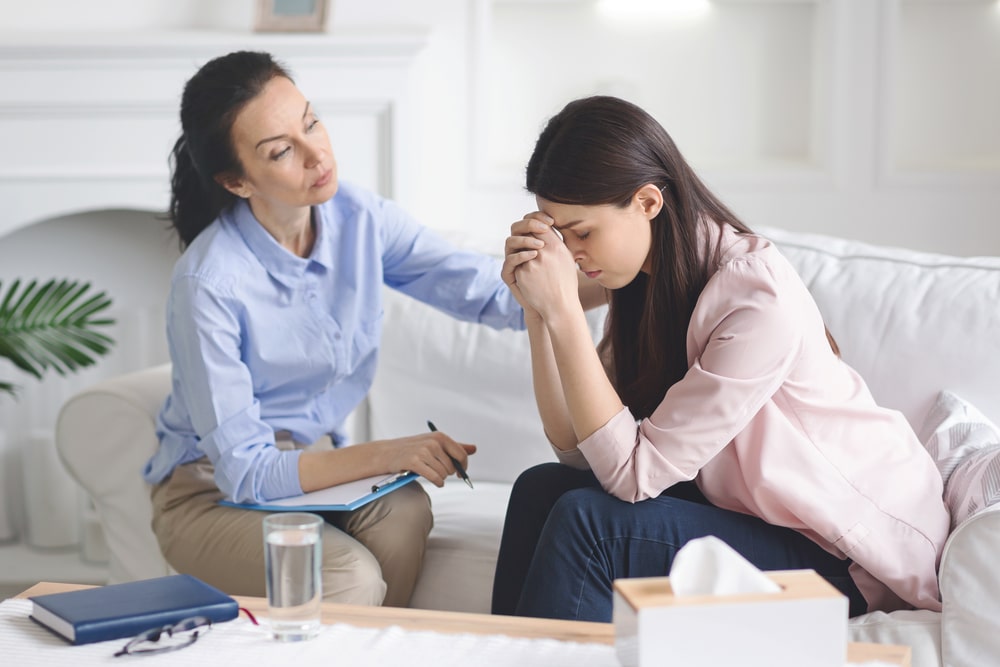 Caring therapist comforting a patient for drug addiction treatment covered by insurance