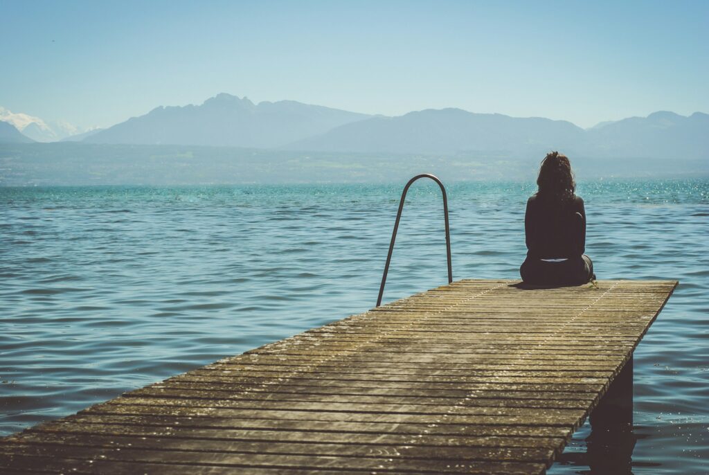 A woman sitting at the end of a dock symbolizes the loneliness people with mental illness often experience.