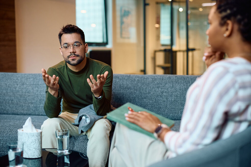 Young man talks during one-to-one session with therapist as part of heroin addiction treatment